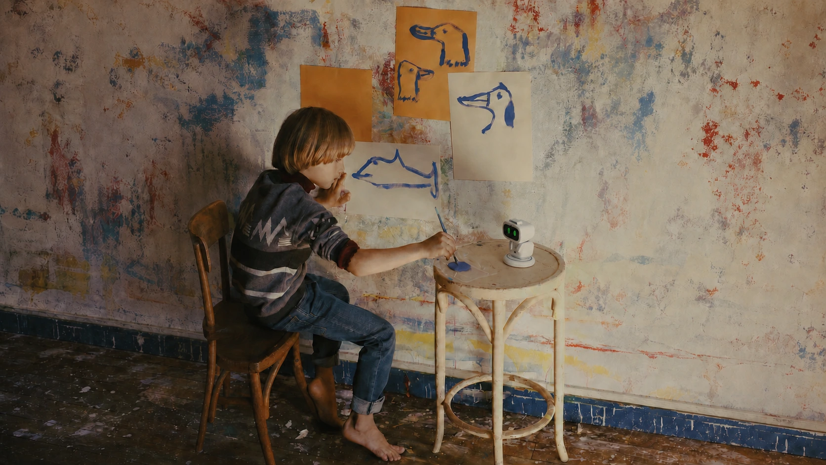 A child painting beside a small robot in an art studio